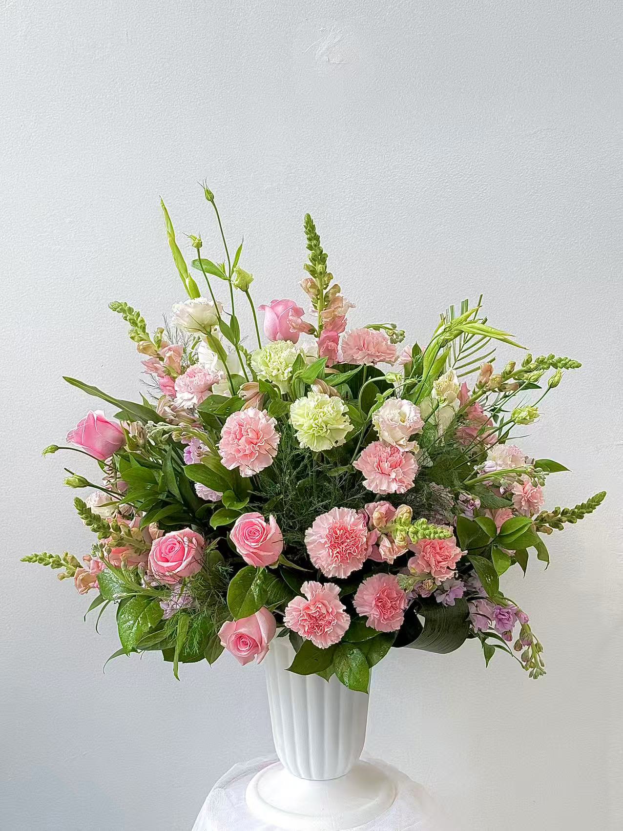 Pink roses and carnations arranged in a white vase