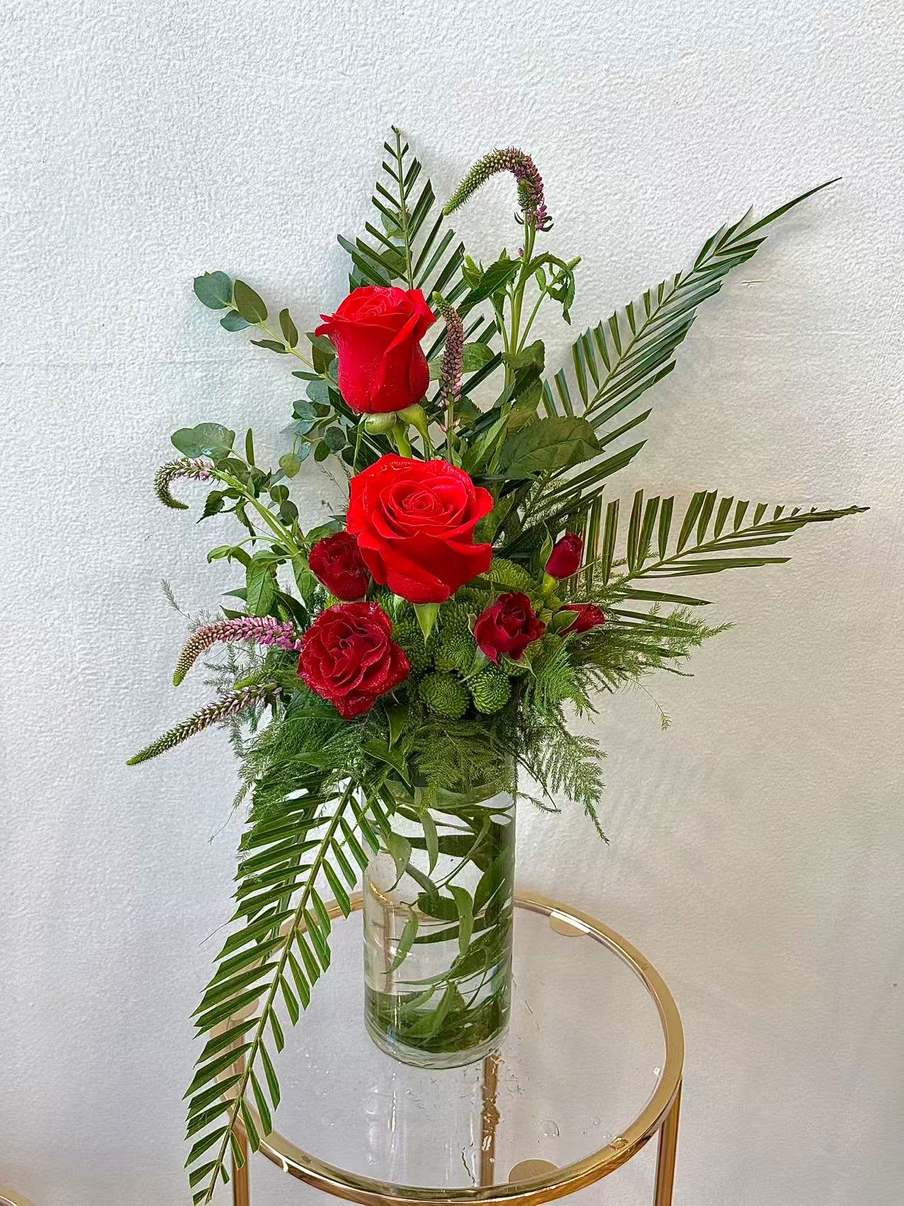 Elegant Red Rose Vase - A sophisticated vase arrangement featuring vibrant red roses accented with lush greenery and tropical foliage. This elegant design adds a touch of romance and timeless beauty to any space, making it perfect for anniversaries, celebrations, or heartfelt gifts.