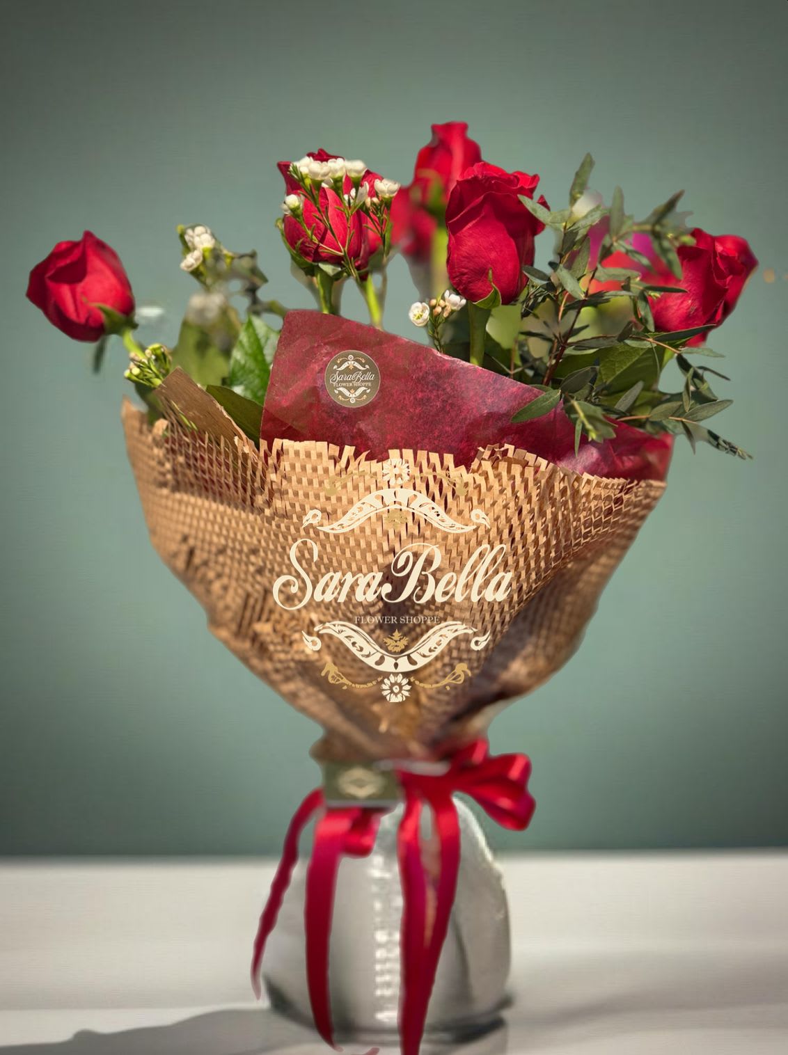 Bouquet of red roses wrapped in brown paper with a red ribbon