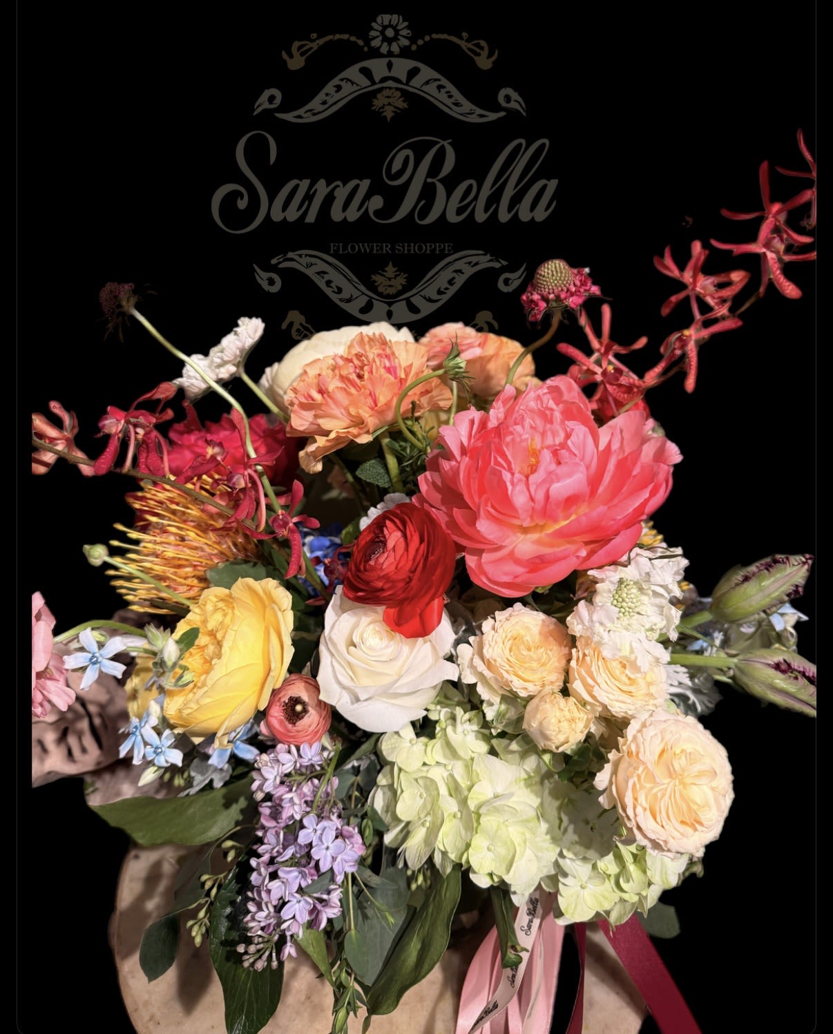BLOOMING SUNSET - A vibrant, garden-style bouquet featuring lush peonies,elegant roses,ranunculus,hydrangea,and seasonal blooms in soft pastels and bold coral tones.