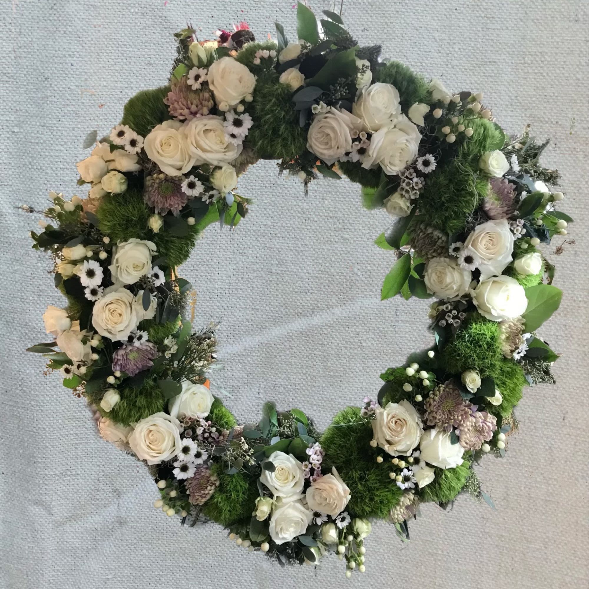 Heart-shaped floral wreath with white roses and green moss