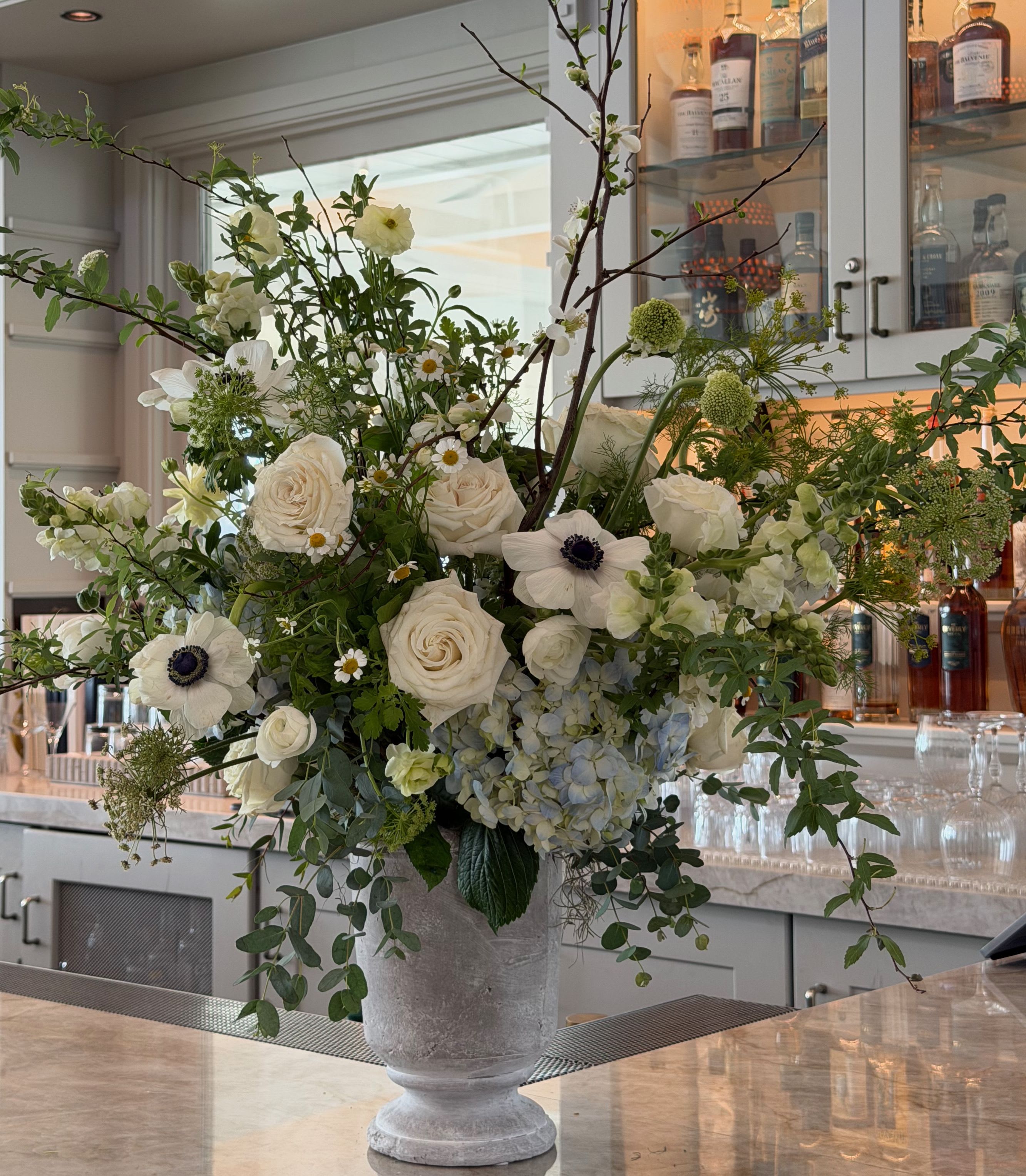 Large white floral arrangement in a gray pedestal vase