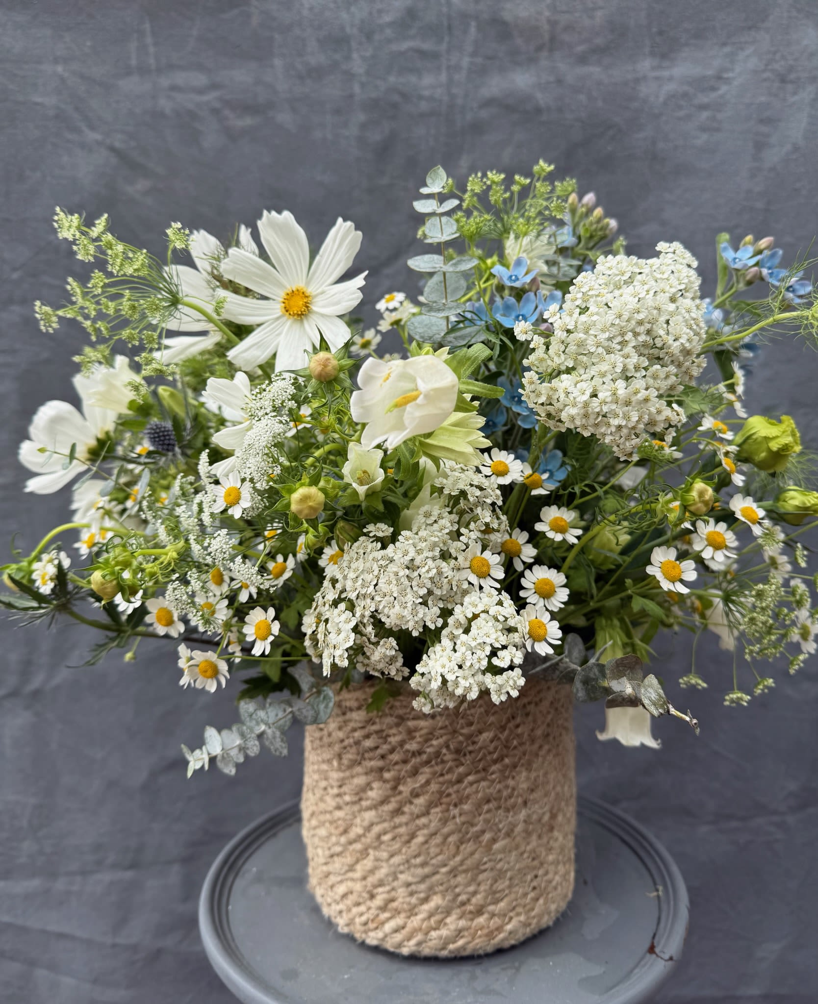 Mixed white and blue flowers arranged in a rope-wrapped vase