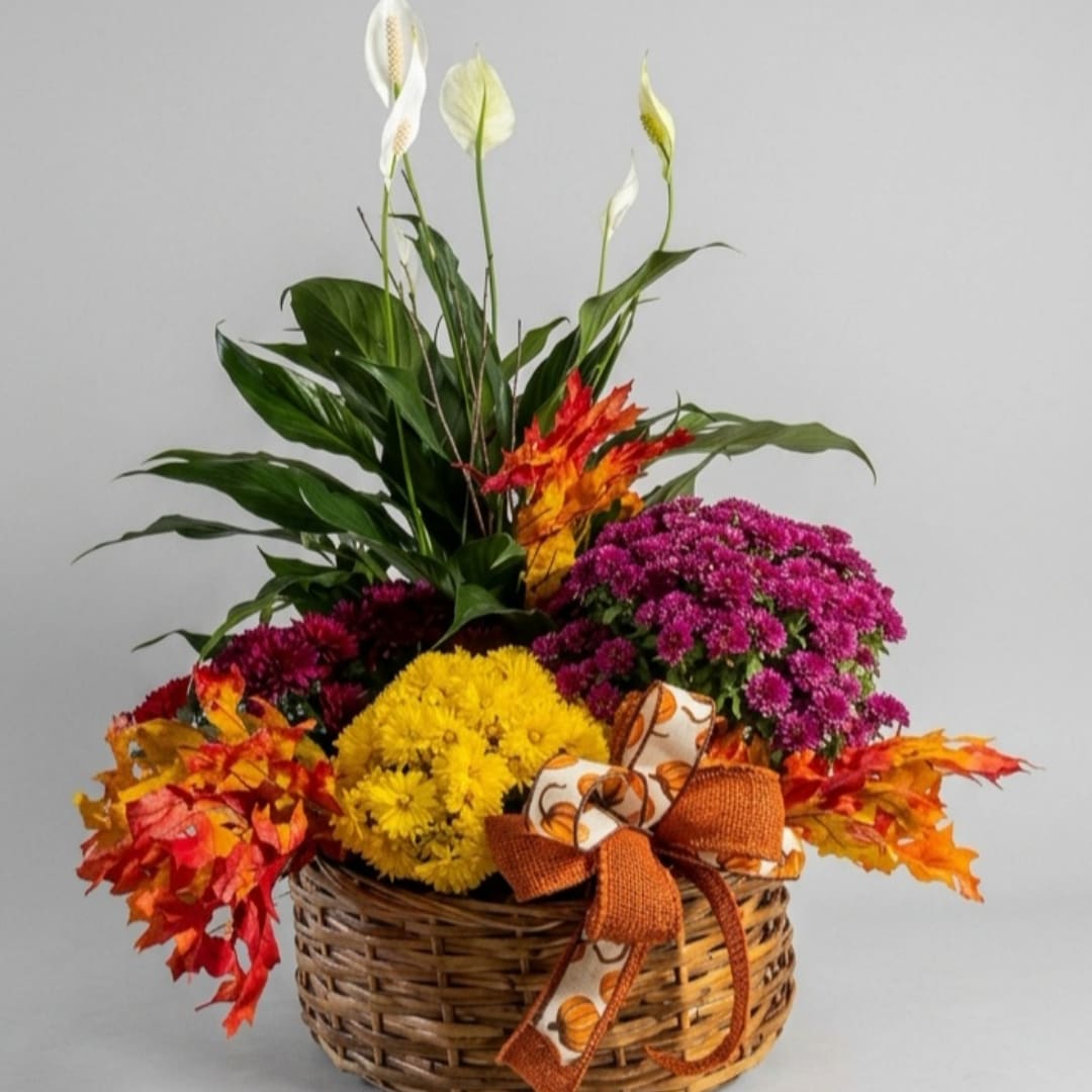 Autumn floral basket with white peace lilies, mums, and fall leaves