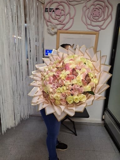 Large bouquet of pastel roses with butterfly accents and layered wrapping