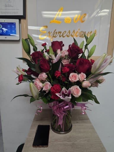 Bouquet of red and pink roses with lilies in a glass vase