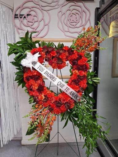 Heart-shaped red floral standing wreath on an easel with a white ribbon