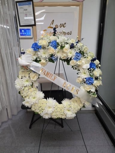 Large floral wreath with white and blue flowers on a stand