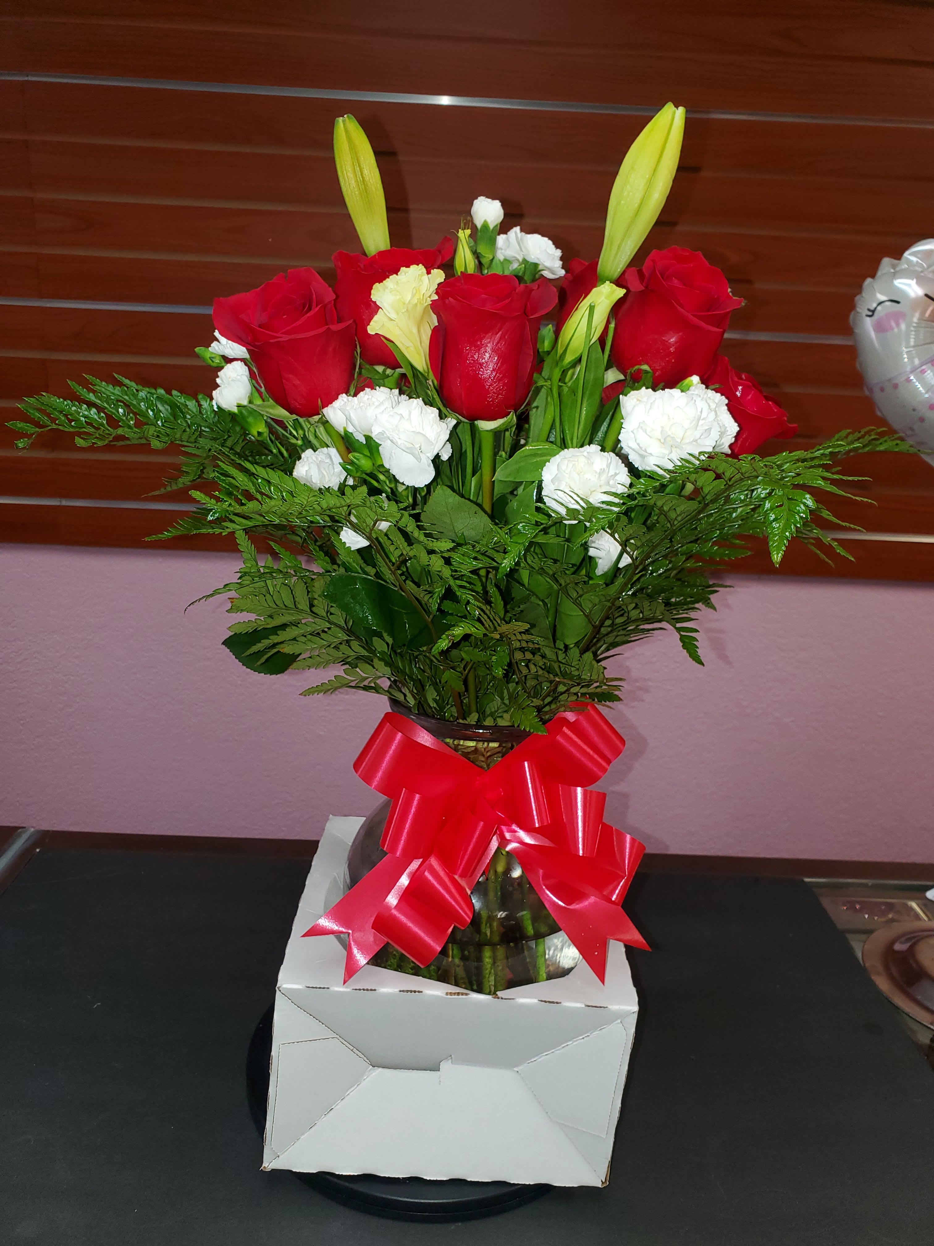 Red roses and white carnations in a glass vase with a red ribbon