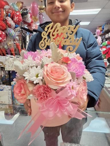 Pink and white flower arrangement with a gold "Happy Birthday" topper