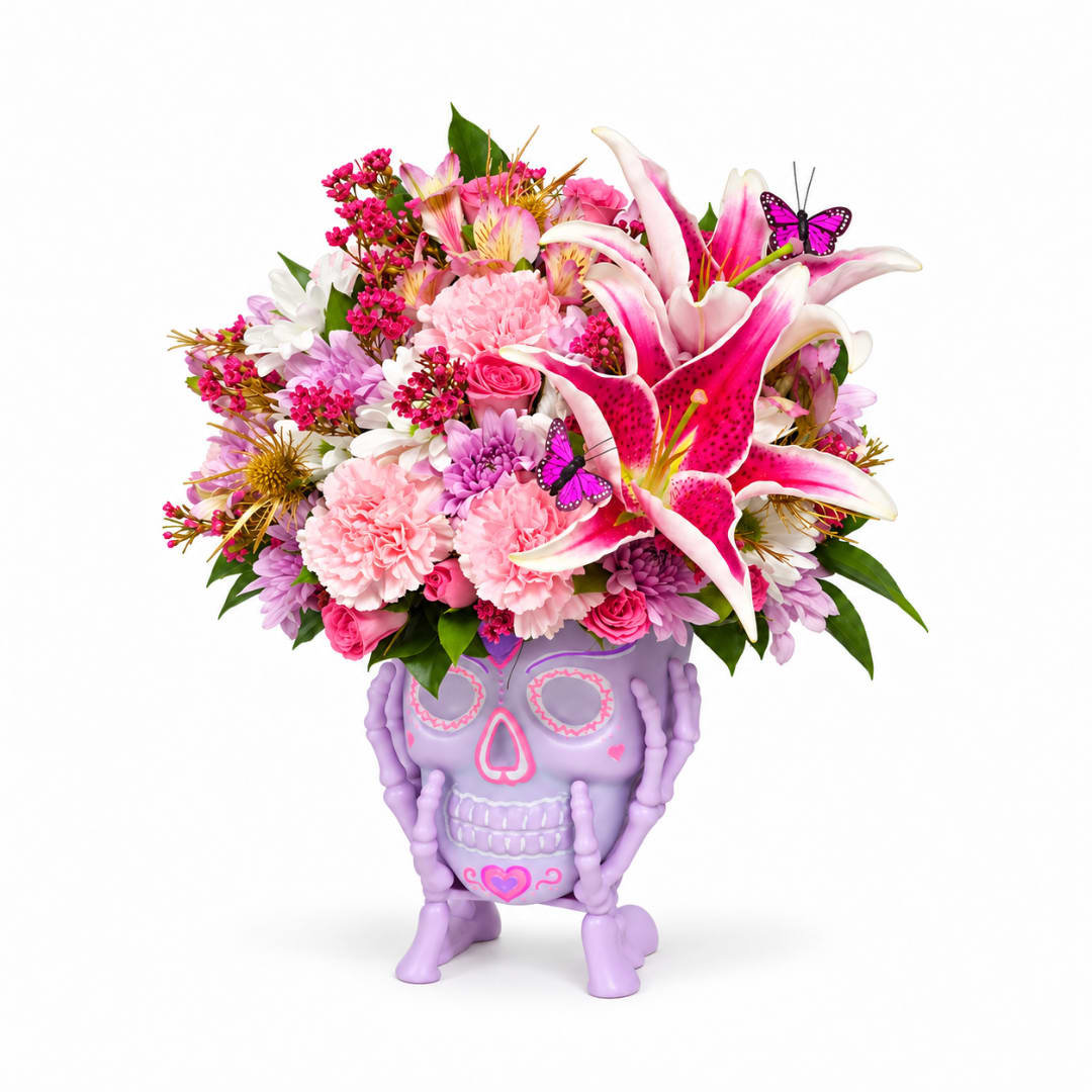 Pink and white flower arrangement in a purple skull planter
