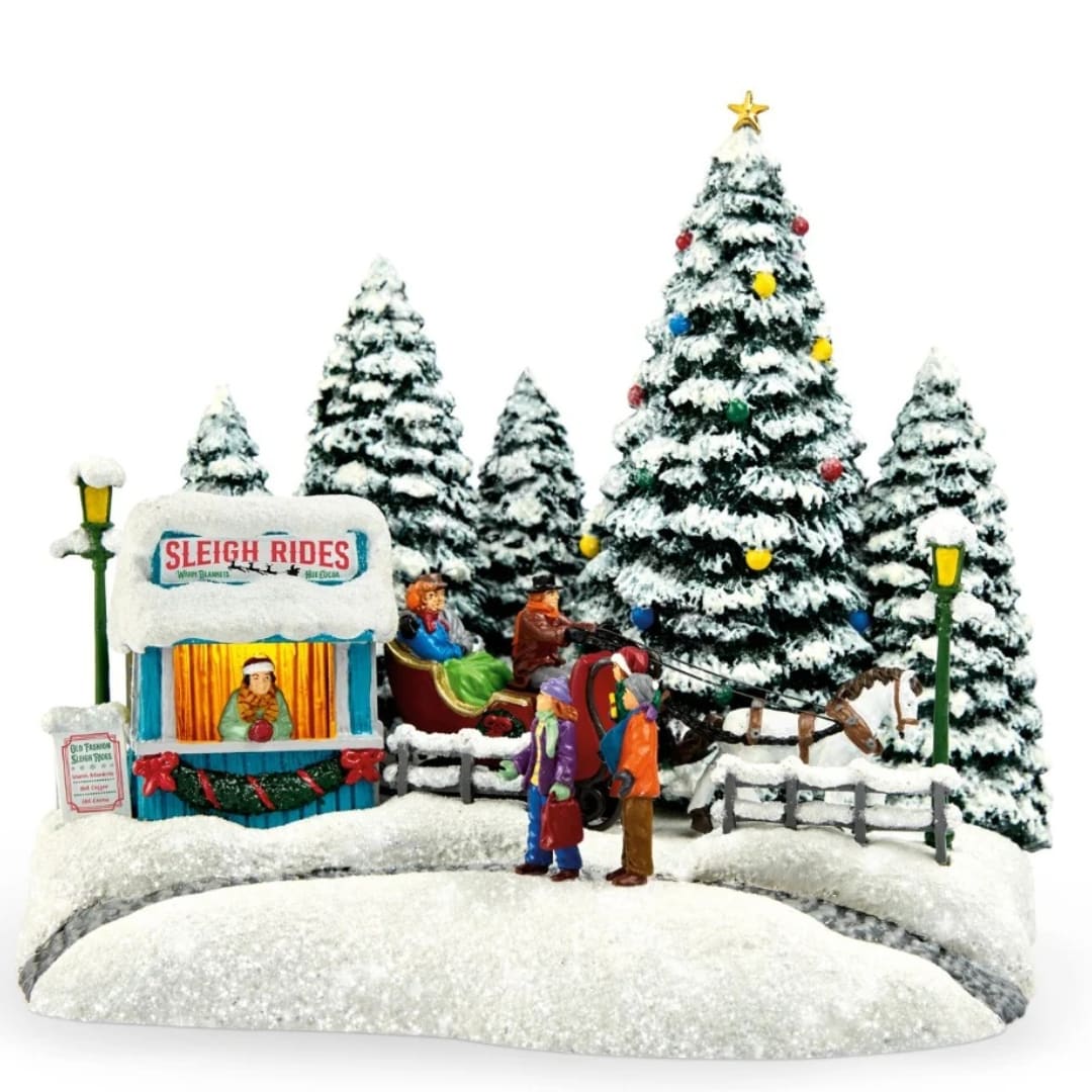 Snowy Christmas village scene with a sleigh ride booth, trees, and figurines