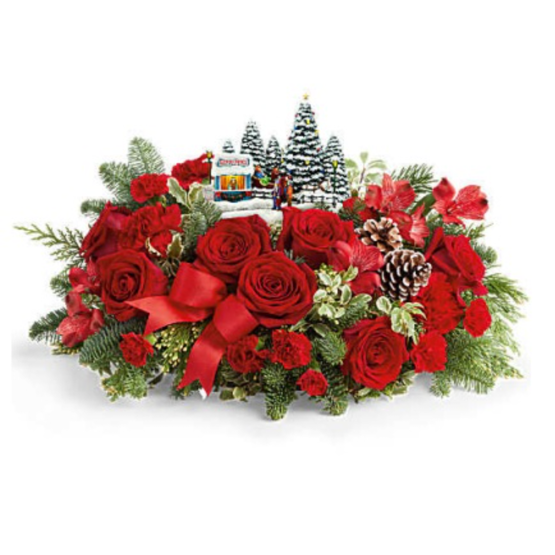Red roses and carnations arranged with pinecones and a small Christmas village scene