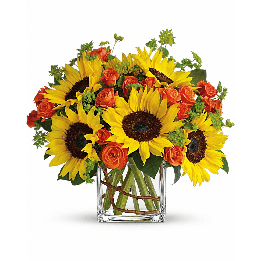 Sunflowers and orange roses arranged in a clear square vase