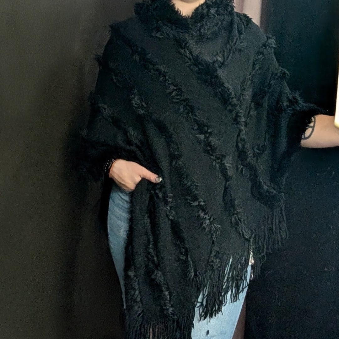 Person wearing a black fringed shawl over jeans