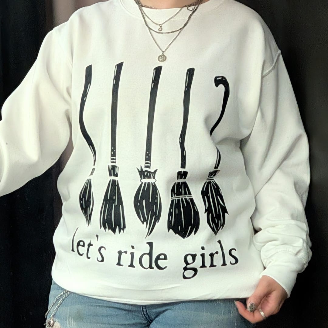 Person wearing a white sweatshirt with black broom graphics and text