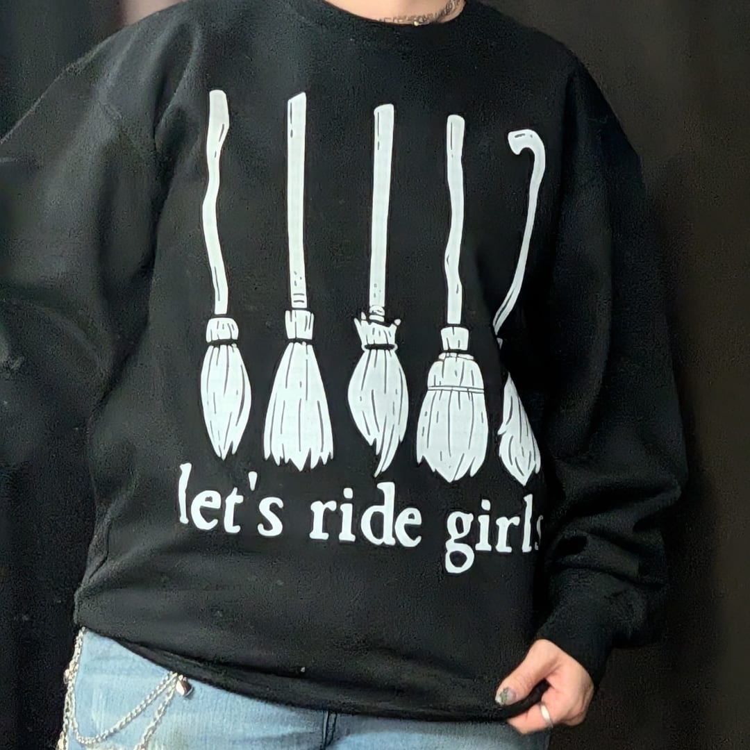 Person wearing a black sweatshirt with broom graphics and text