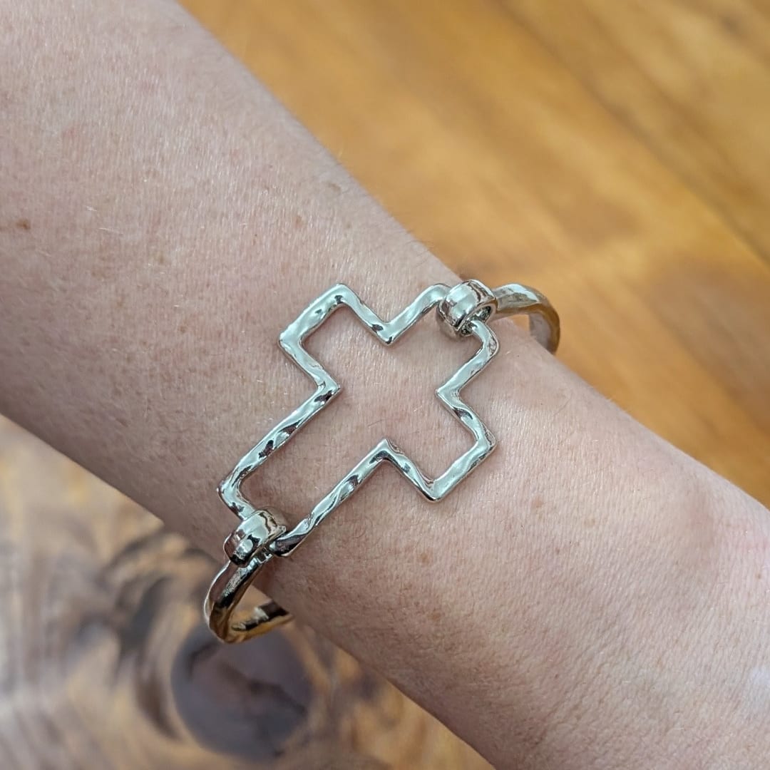 Silver cross-shaped bracelet on a wrist