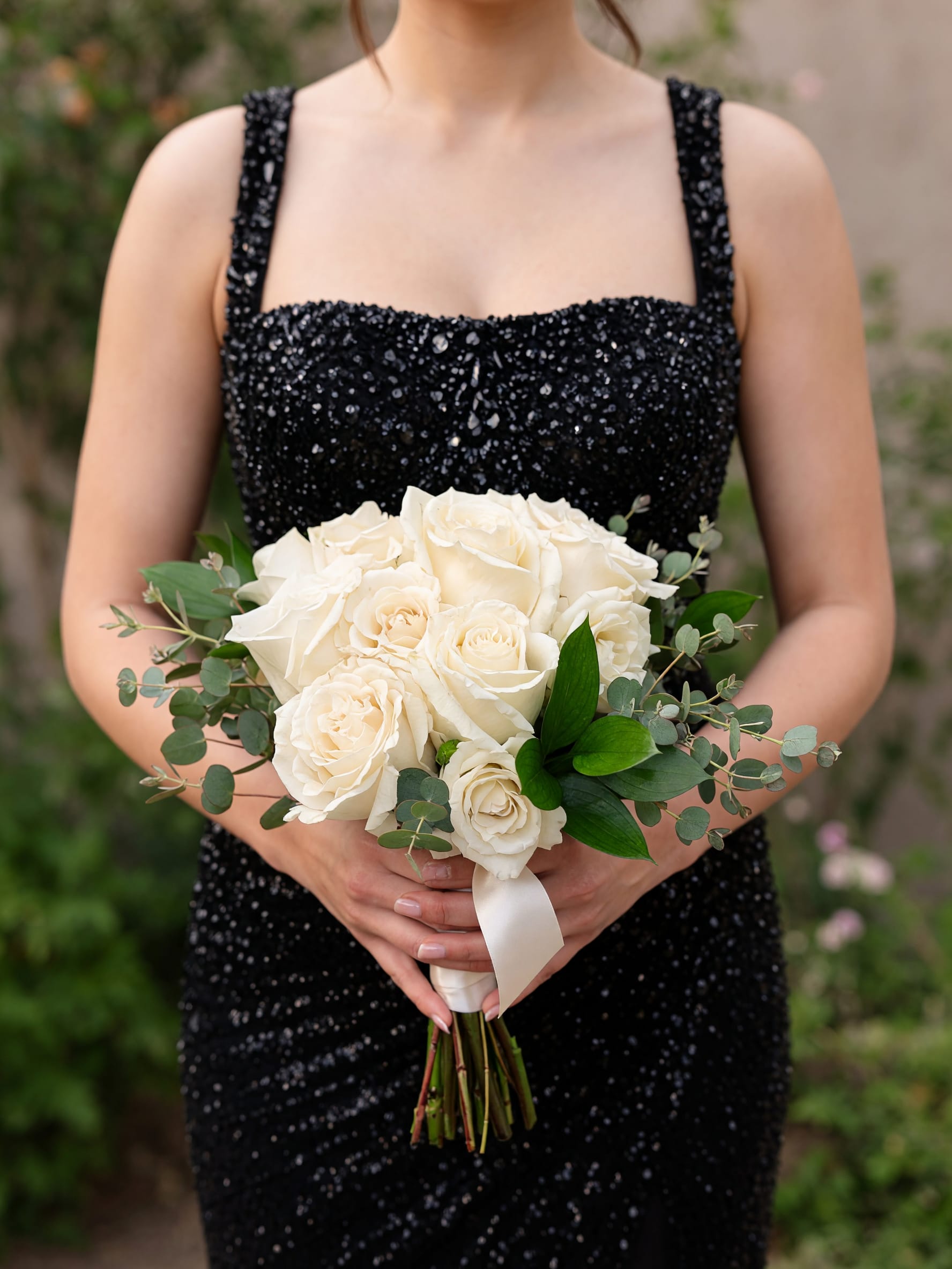 White Nosegay  - Creamy white roses gathered in a rounded, hand-tied nosegay create an elegant focal point that feels both classic and quietly modern-perfect as a wedding posy, prom bouquet, or any romantic gesture. The compact shape puts the blooms front and center so the person you're celebrating will look and feel effortlessly refined the moment they carry it.  Soft eucalyptus-like foliage and glossy green leaves frame the roses for gentle texture and a fresh, green contrast against the white petals. A pale satin ribbon finishes the stems, lending a polished, formal touch that complements bridal gowns or evening wear. Compact and easy to hold, this arrangement is designed for close-up moments-ceremony vows, a prom entrance, or a hand-delivered declaration of love-and arrives ready to present with simple care: keep stems trimmed and the bouquet in fresh water until the moment it's given.