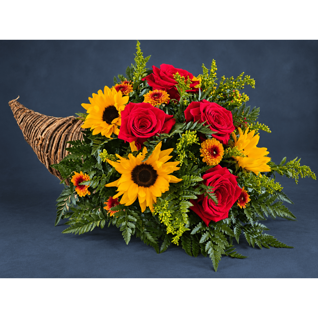 Bouquet of red roses and yellow sunflowers in a wicker cornucopia