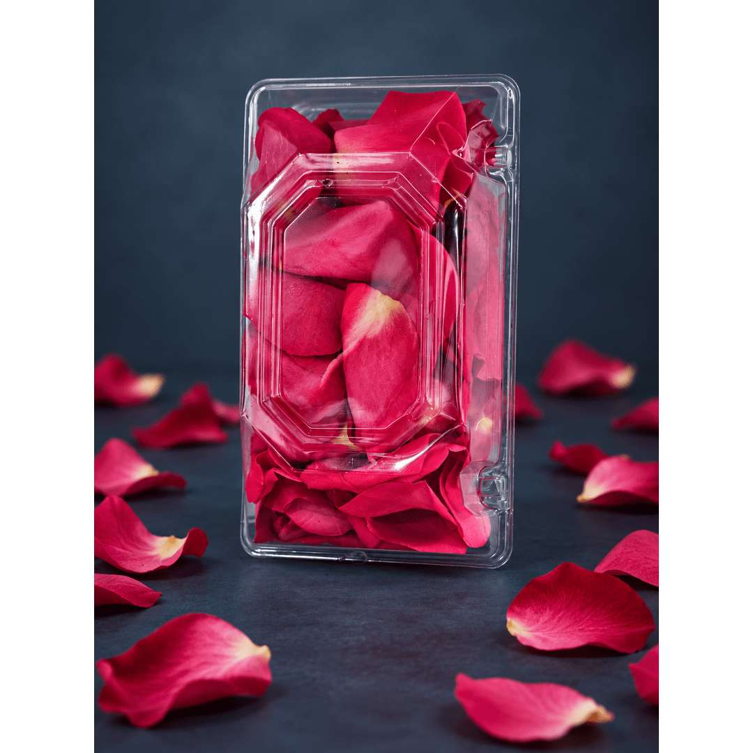 Clear plastic box filled with red rose petals on a dark background