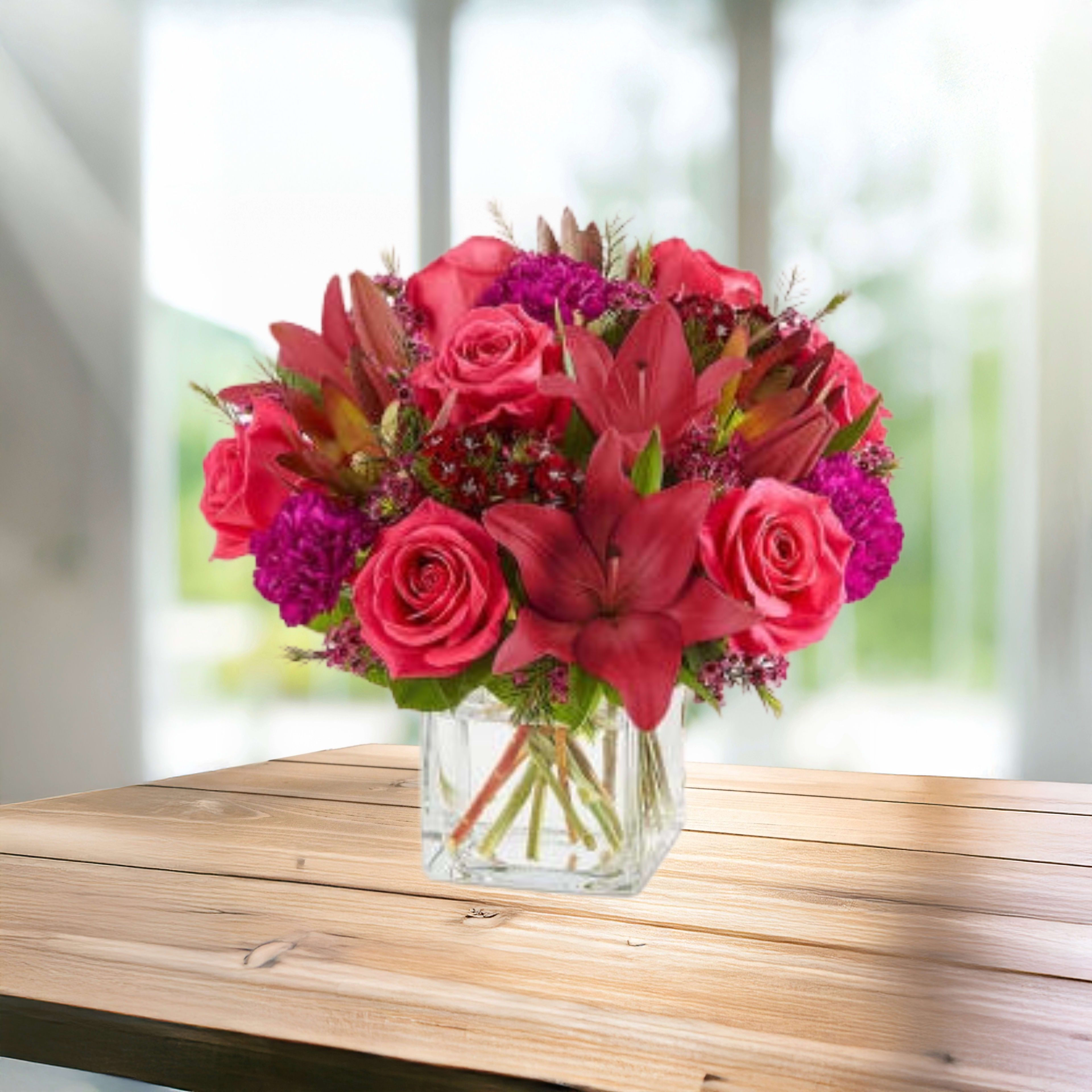 Pink roses and lilies arranged in a clear glass vase