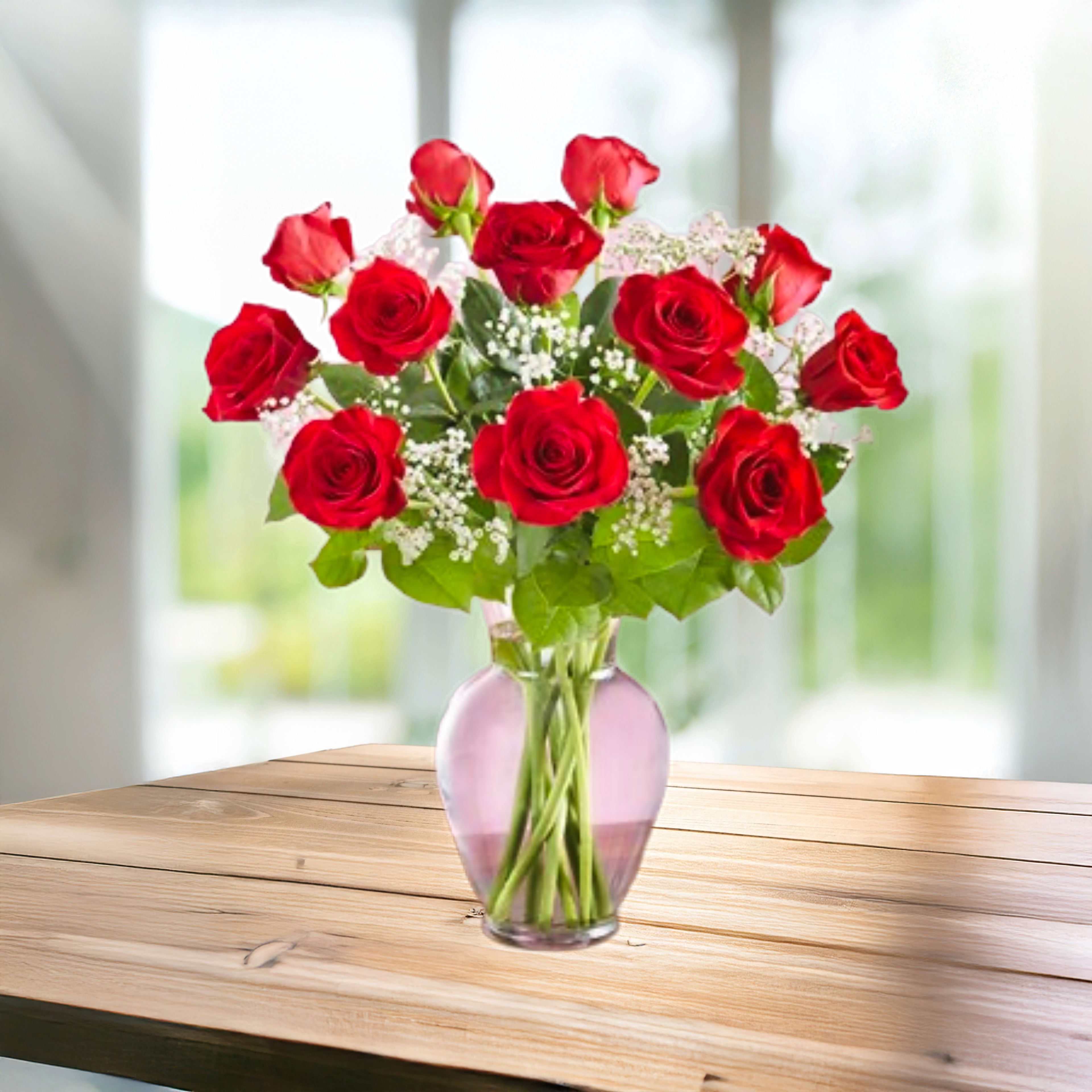 Red roses arranged in a pink glass vase