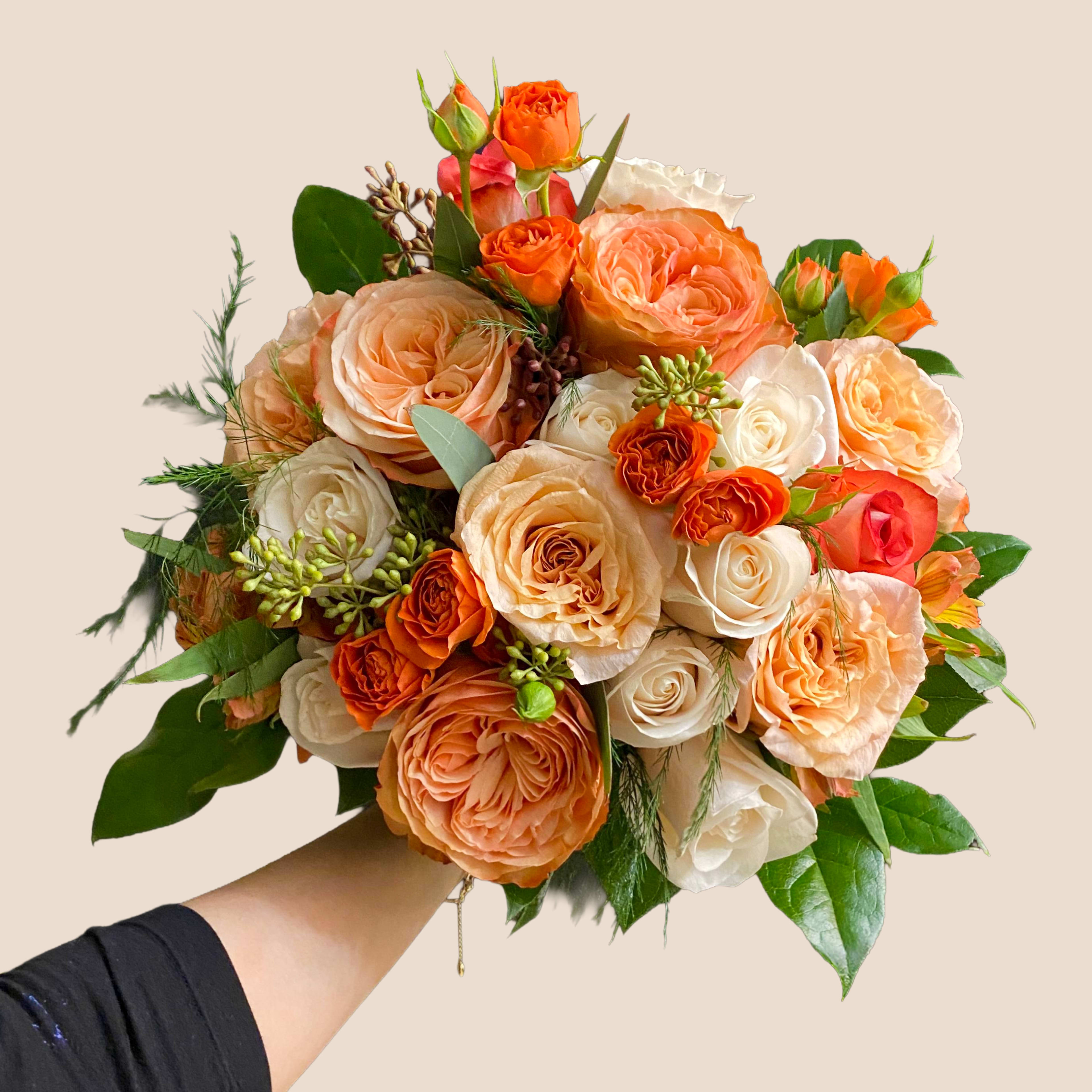 Handheld bouquet of peach, orange, and white roses