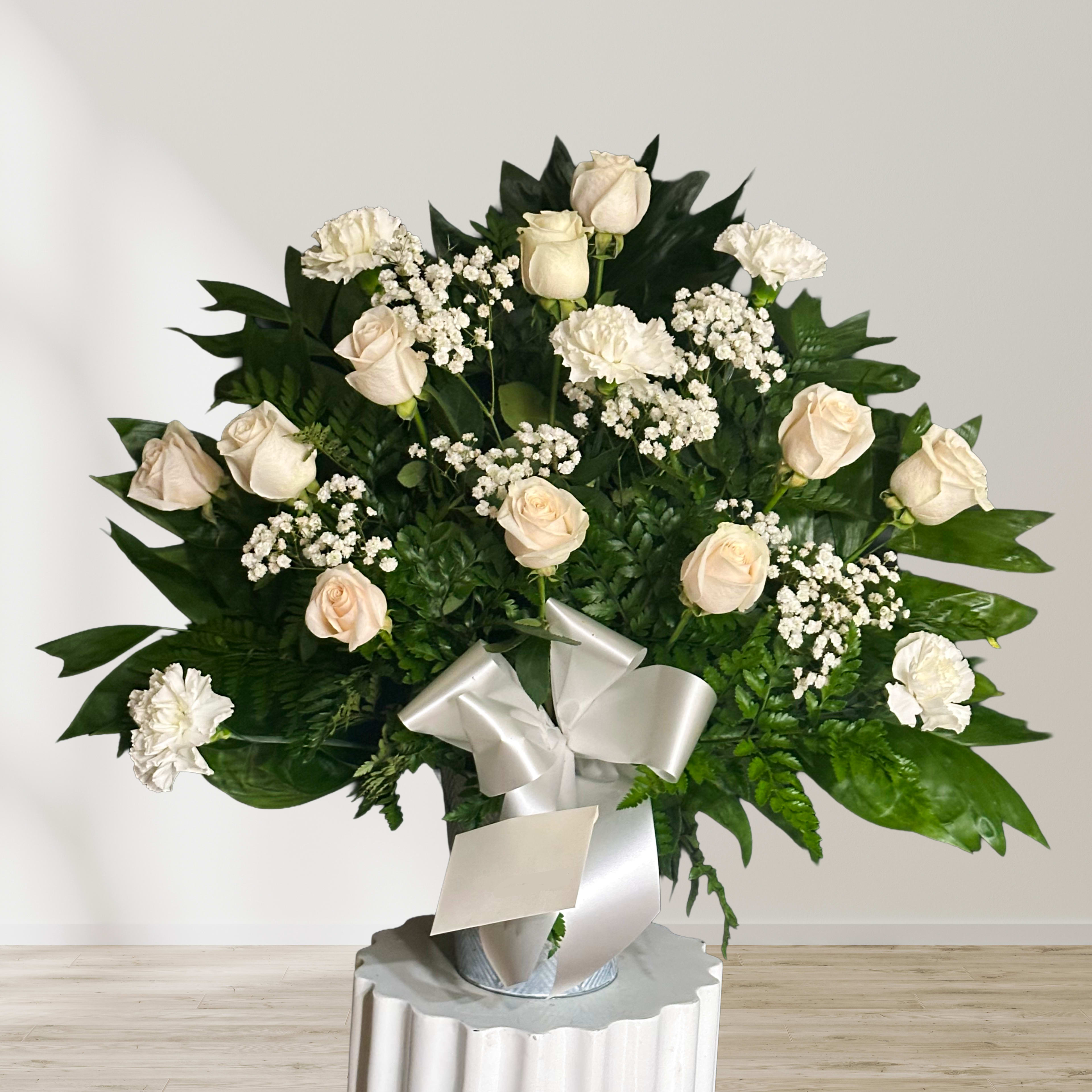 Cream roses and white carnations in a silver vase with a white ribbon