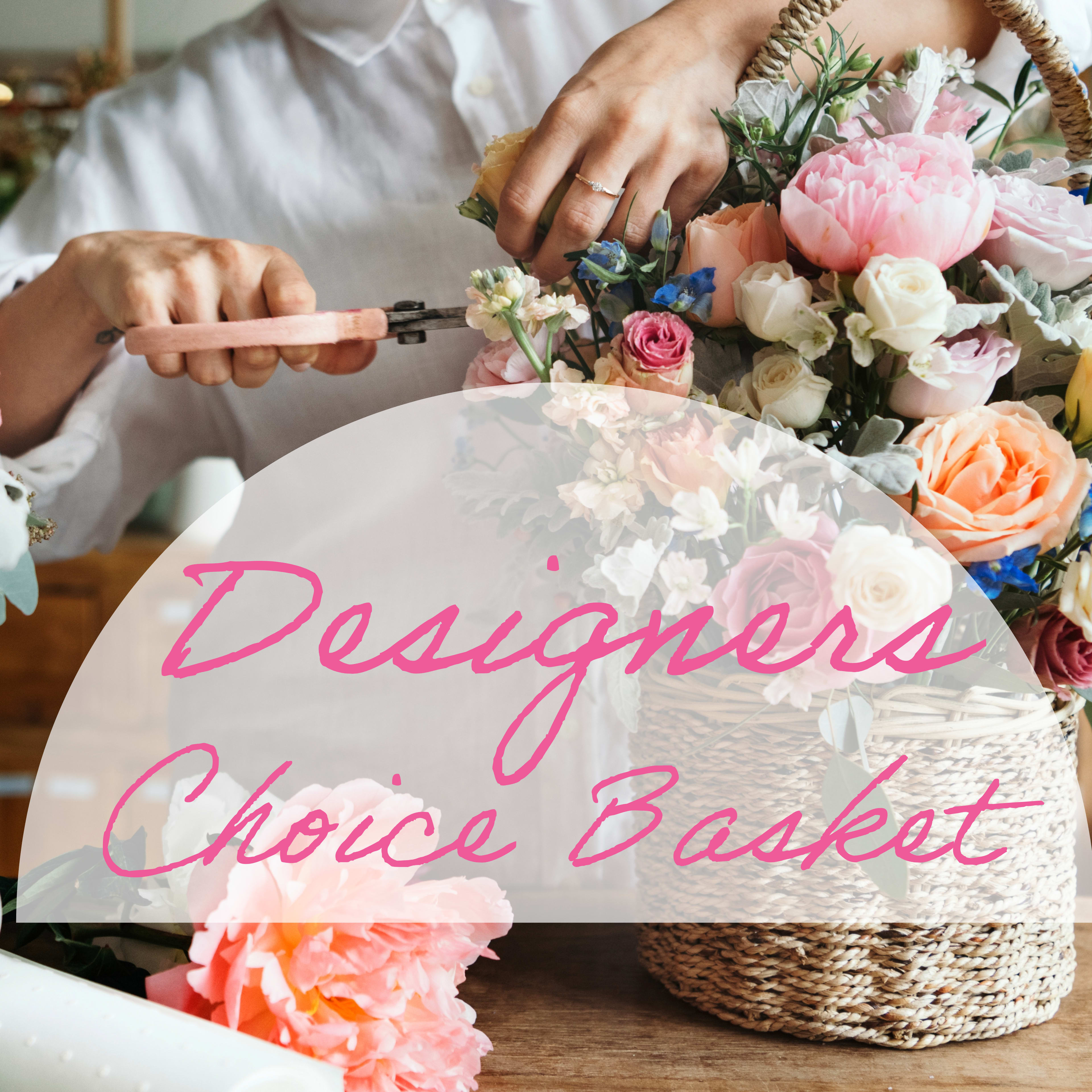 Designers Choice Basket - Soft pink flowers and clustered roses mingle with peach and white blooms in this Designers Choice basket bouquet, a charming flower arrangement perfect for a birthday bouquet, Mother's Day, or a spring celebration. The rounded, hand-arranged composition reads romantic and cheerful-an ideal gift to make the person you're thinking of feel truly celebrated and seen.  The arrangement features large rose blossoms, cheerful daisies and complementary filler flowers in soft pastels, with small blue accents that add a fresh contrast to the palette. Flowers arrive tucked into a woven basket that gives the piece a rustic, handcrafted feel; a pair of floral scissors is included for easy trimming and care. The full, rounded shape and mixed textures create a lush, tactile display that sits beautifully on a table or entryway.  This basket is well suited for moms, sisters, friends, or anyone who loves a soft, feminine bouquet for anniversaries, thank-you moments, or springtime surprises. To keep blooms fresh, trim stems slightly and refresh the water every couple of days; sizing and exact flower varieties may vary with seasonal availability as this is a Designers Choice arrangement.