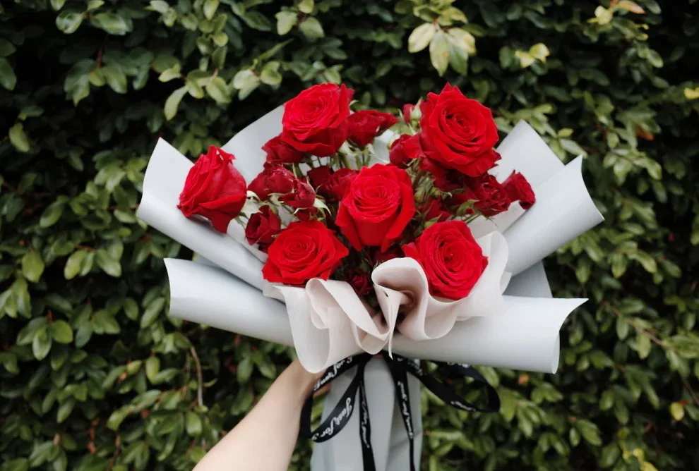 Classic Red Rose Bouquet - Bold expression of love with a modern twist. This bouquet features fresh red roses—some in full bloom, others just beginning to open—wrapped in soft white and grey paper and tied with a sleek black ribbon inscribed in elegant script. A refined gift for anniversaries, romantic surprises, or any moment that calls for timeless beauty.
