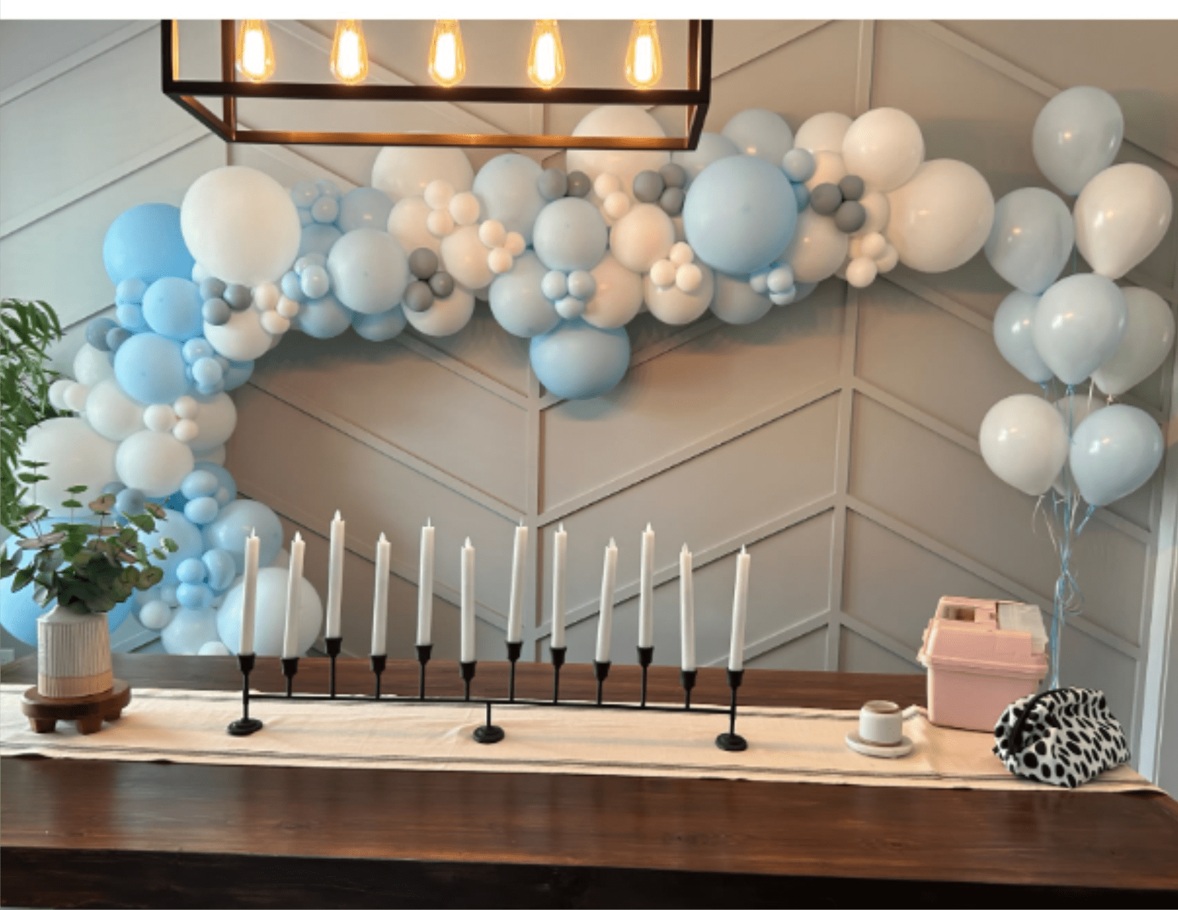 Blue and white balloon garland above a table with candles