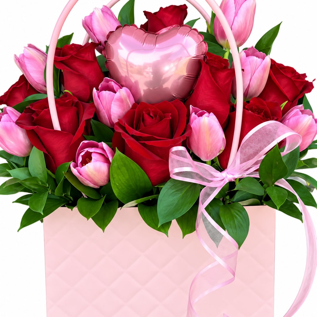 Pink tulips and red roses arranged in a pink gift box with a heart balloon