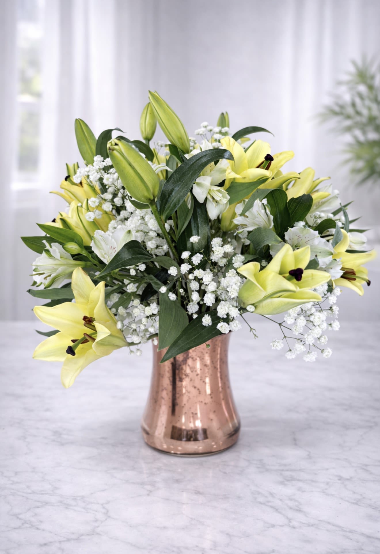 Yellow lilies and white baby's breath in a copper vase