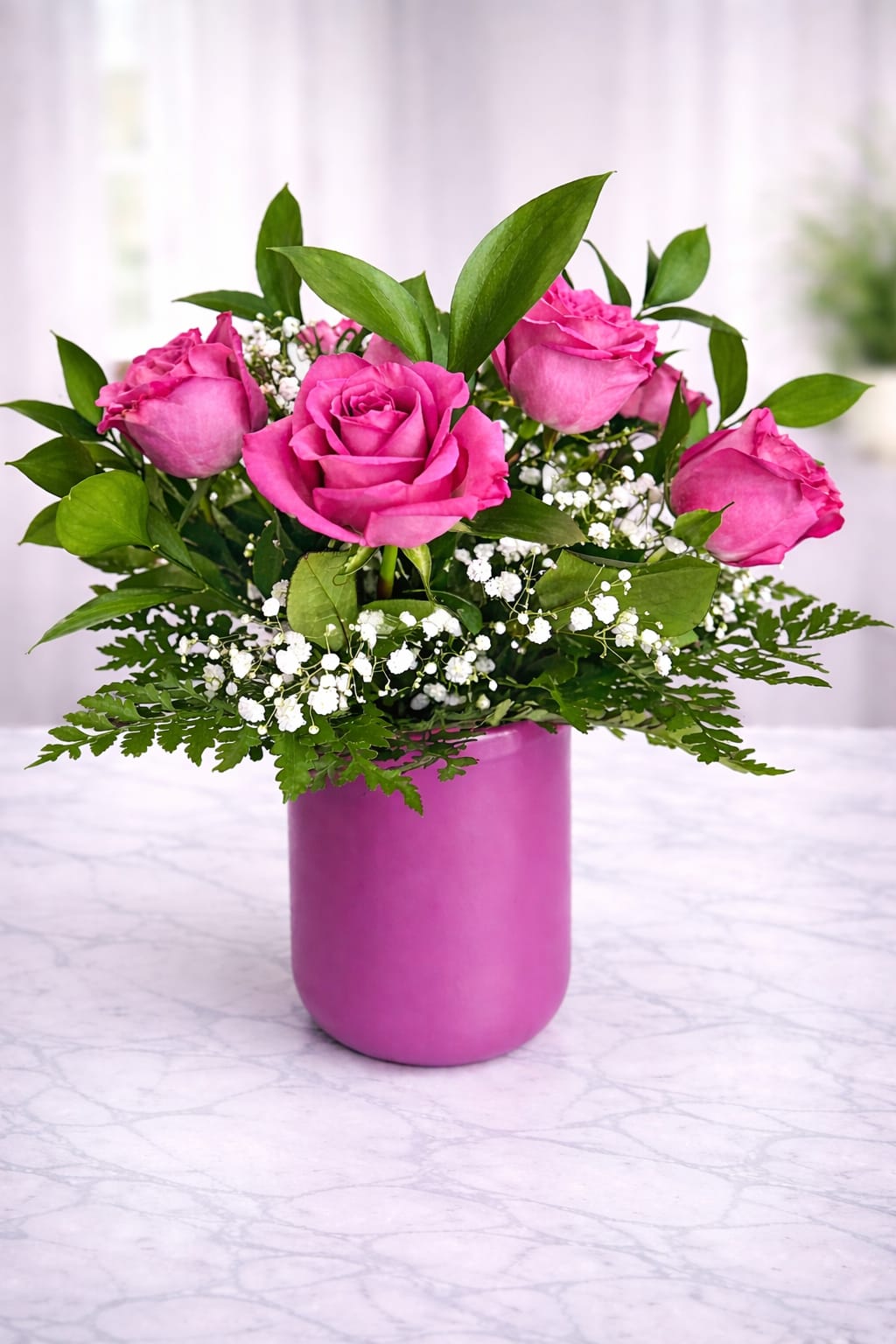 Pink roses arranged in a magenta vase with white filler flowers