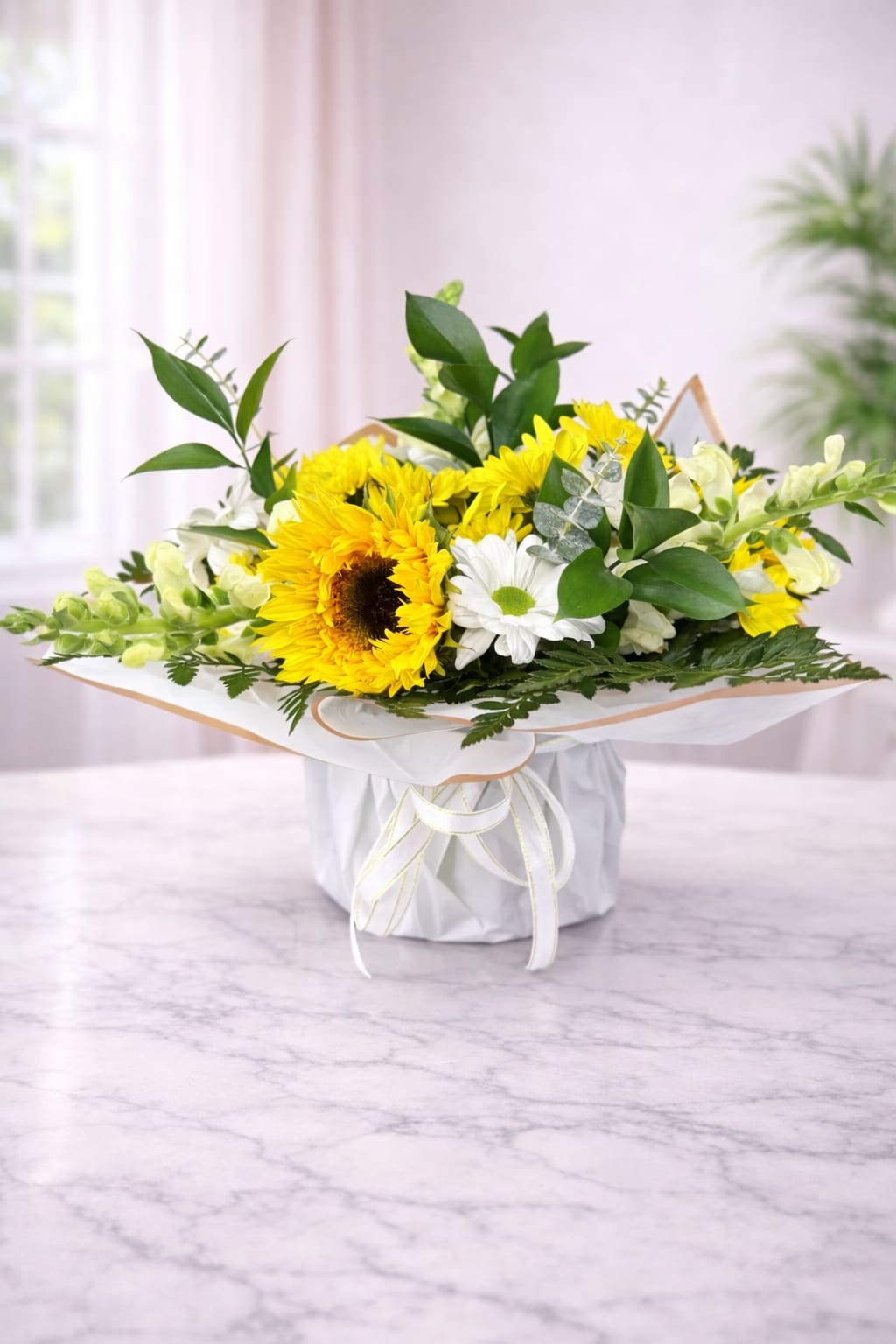 Yellow sunflowers and white daisies in a wrapped bouquet box