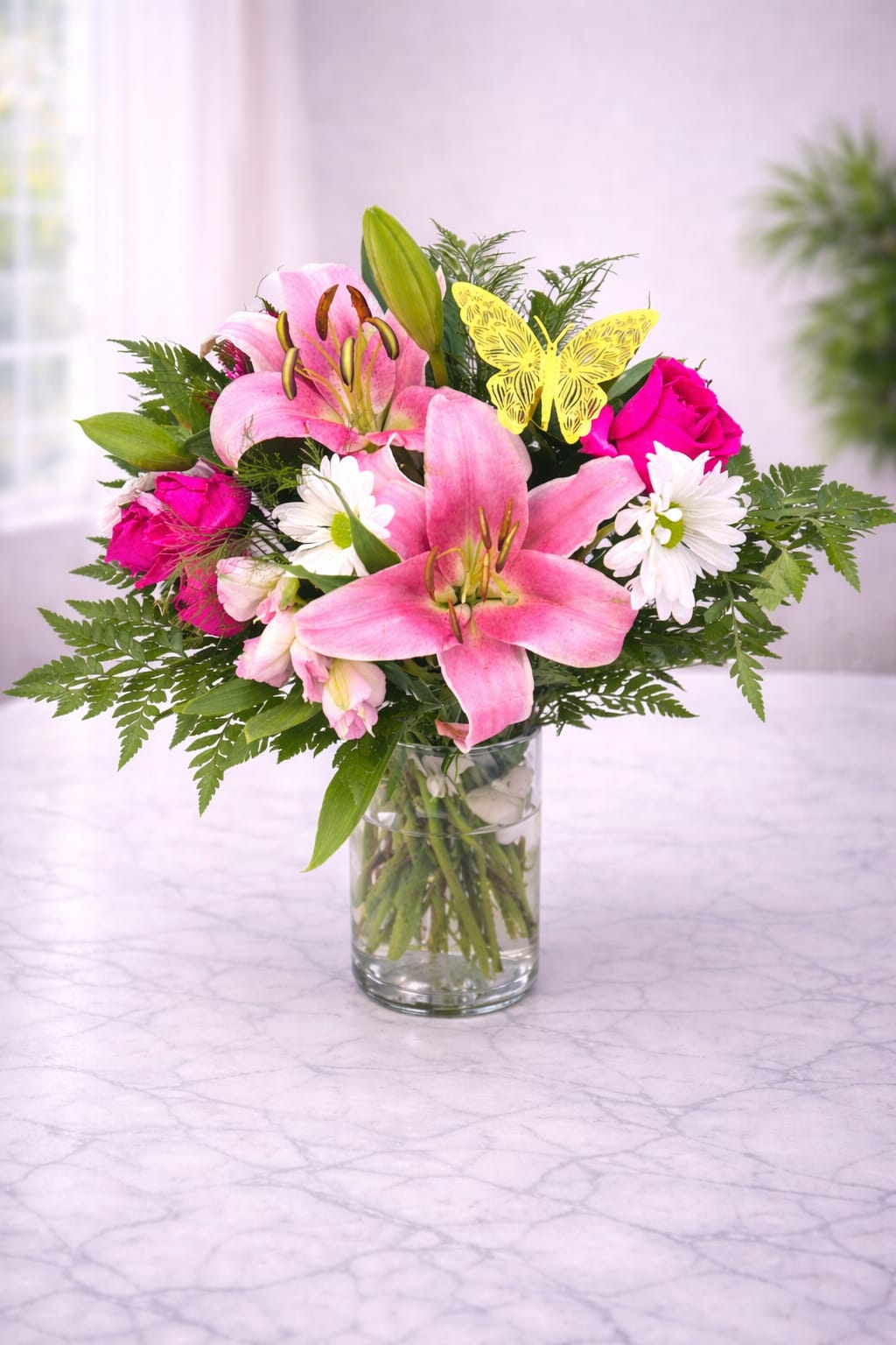 Pink lilies and roses arranged in a clear glass vase
