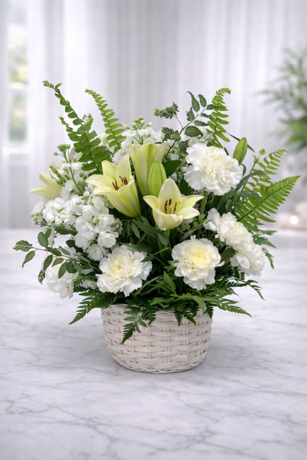 White lilies and carnations arranged in a white wicker basket