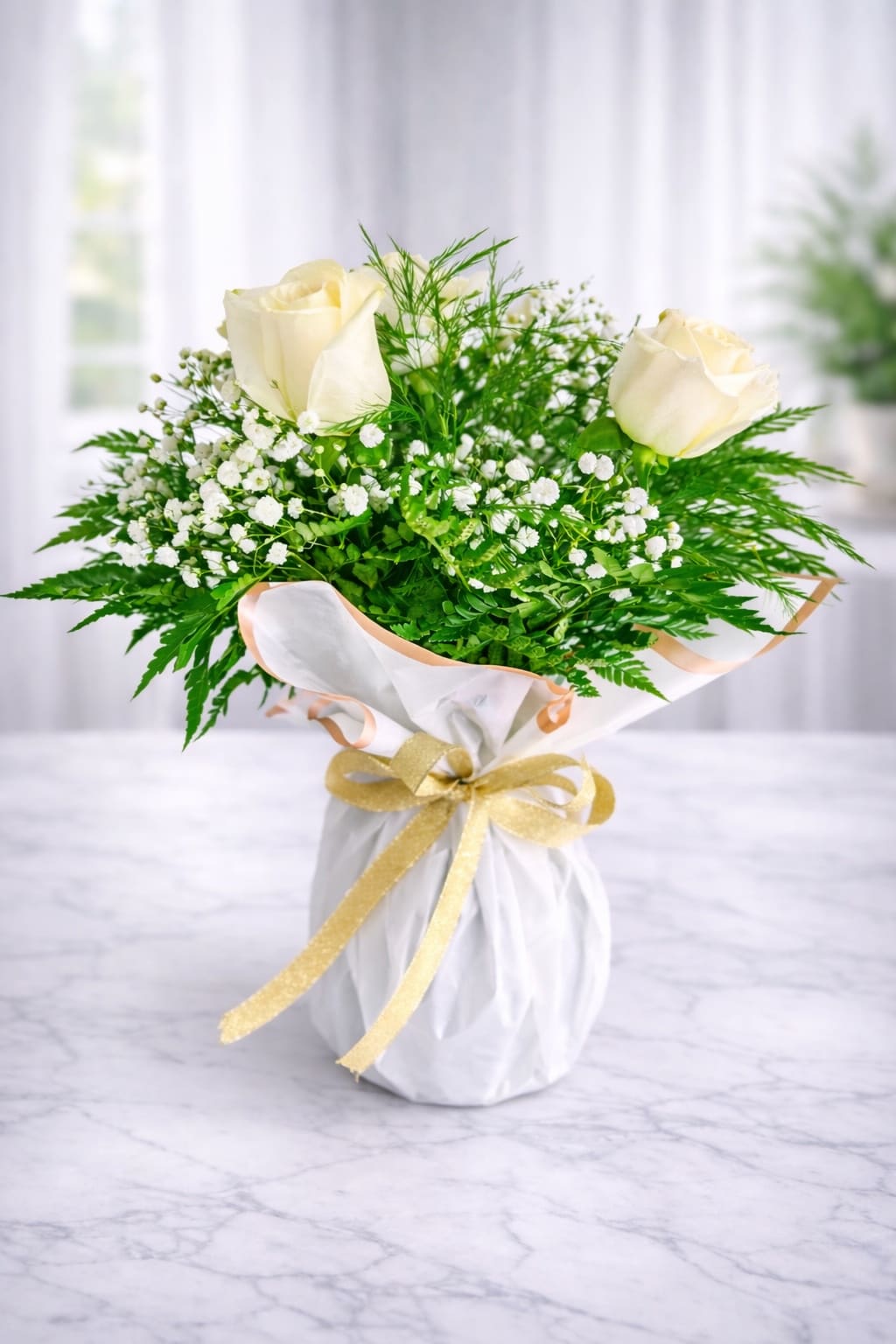 Bouquet of white roses and baby's breath wrapped in white paper with a gold ribbon