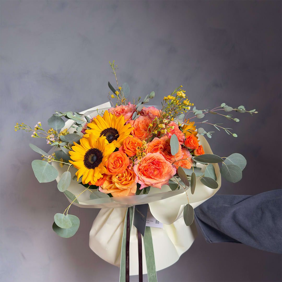 Bouquet of sunflowers and orange roses wrapped in cream paper