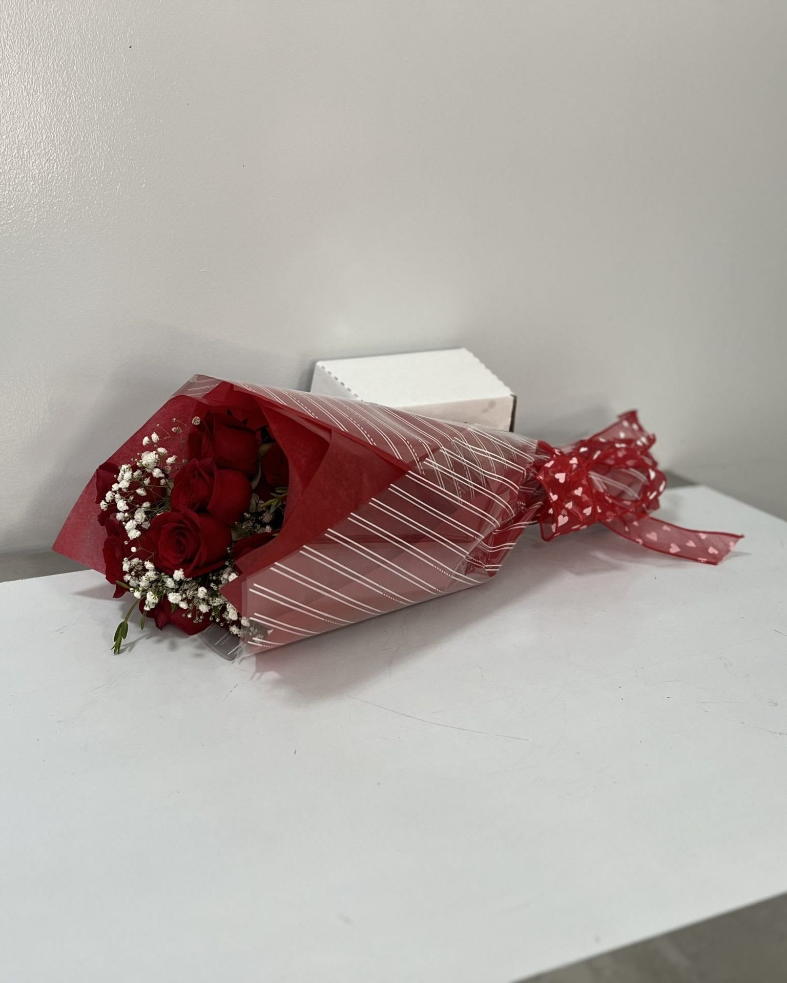Bouquet of red roses wrapped in red paper with white baby's breath