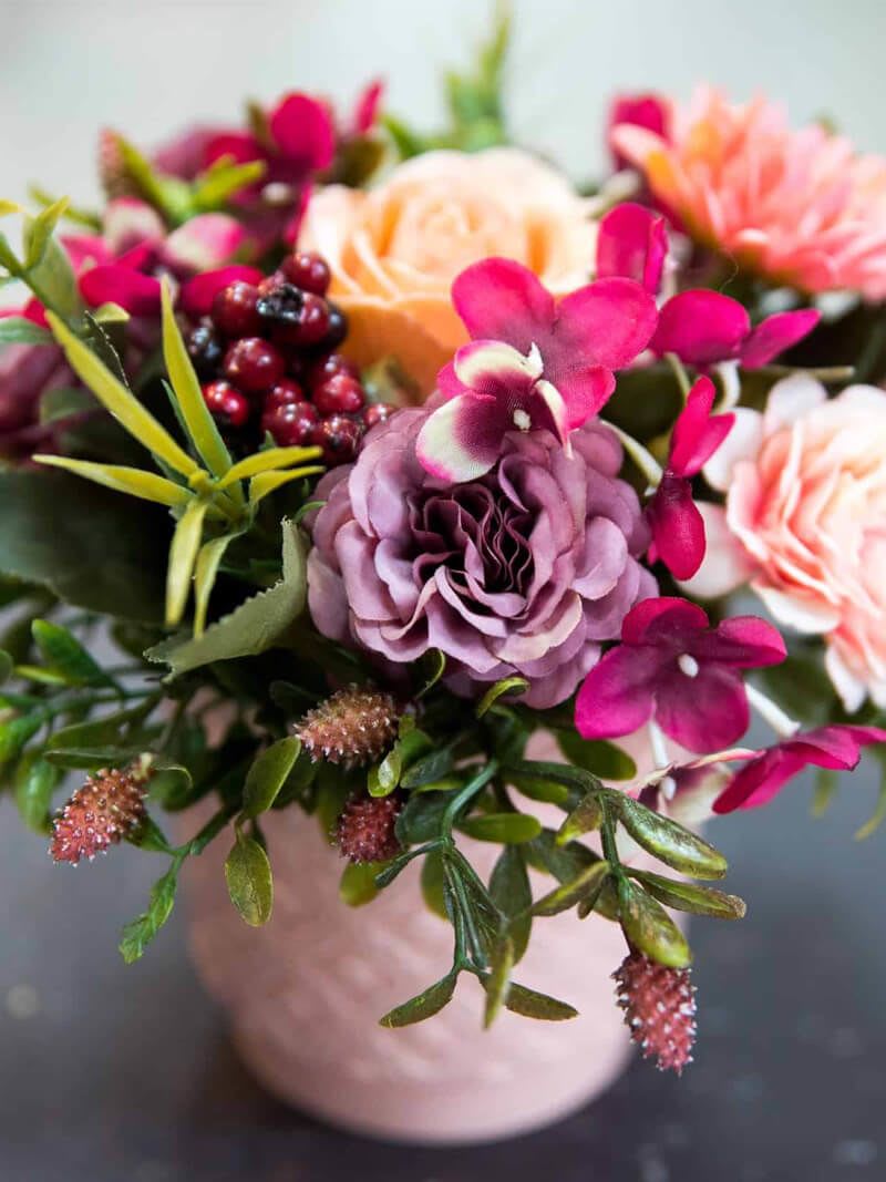 Pink and peach floral arrangement in a pale vase