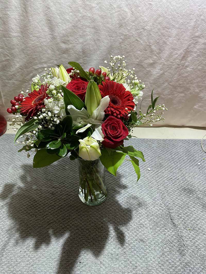 Red roses and gerbera daisies in a clear glass vase