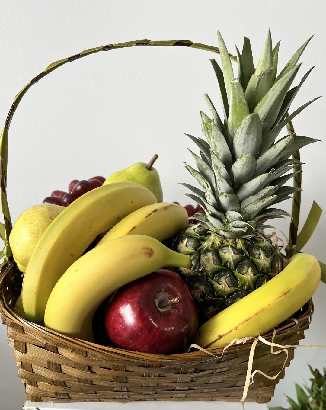Fruit basket with bananas, pineapple, apples, grapes, and pears