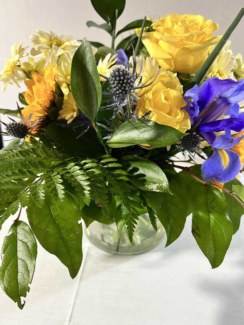 Yellow and blue mixed bouquet in a clear glass vase