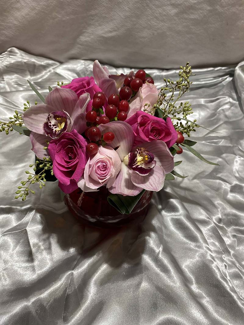 Pink roses and orchids arranged in a red vase