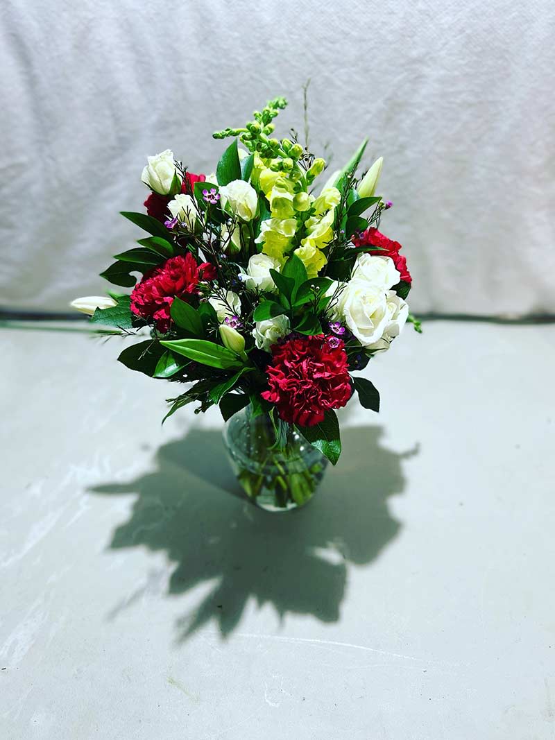 Mixed bouquet of red, white, and green flowers in a glass vase
