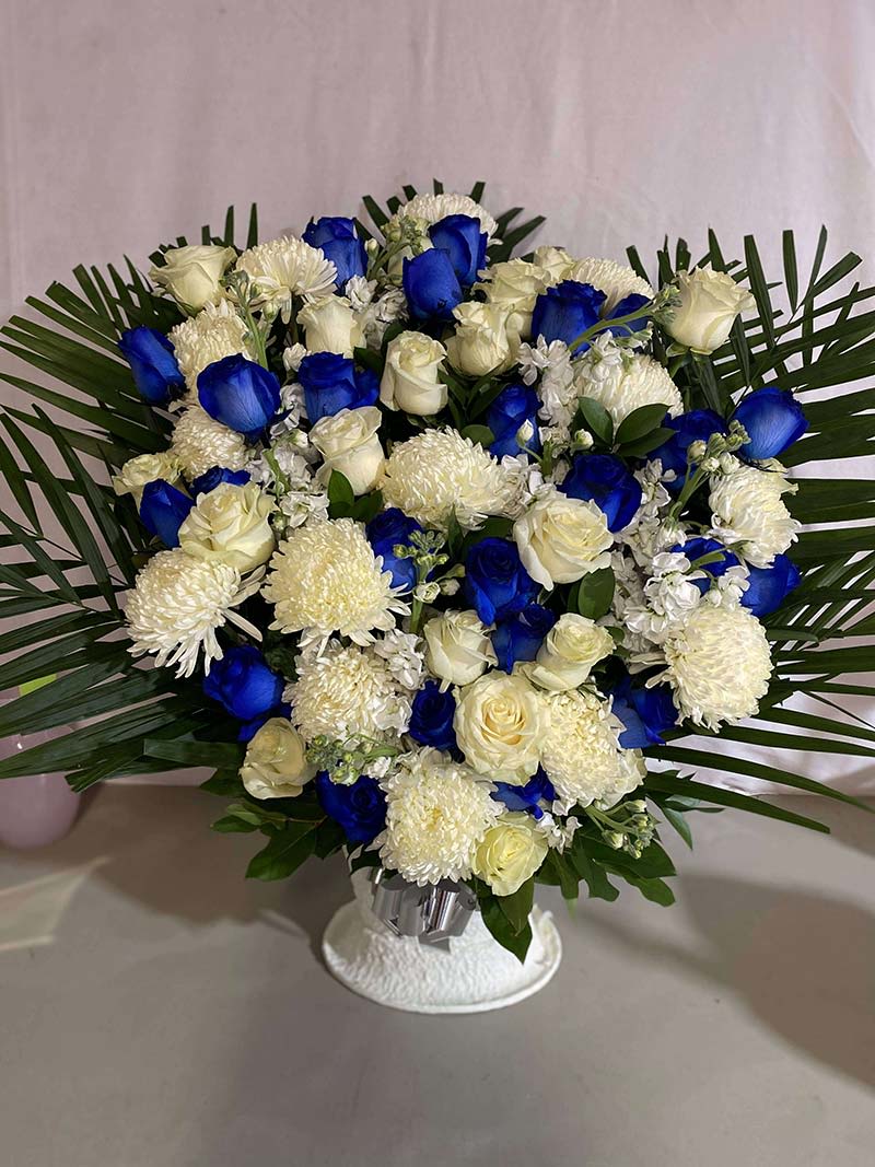 Blue and white rose bouquet with white mums in a vase