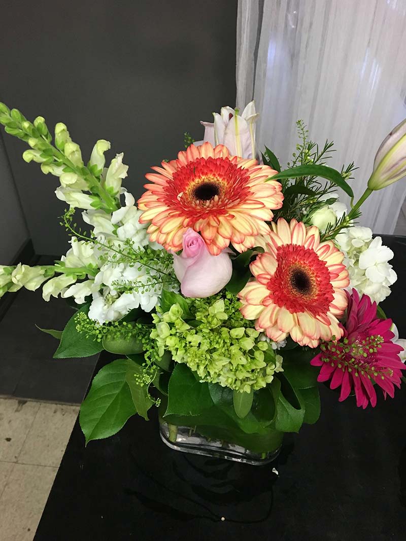 Mixed bouquet with gerbera daisies, snapdragons, and lilies in a glass vase