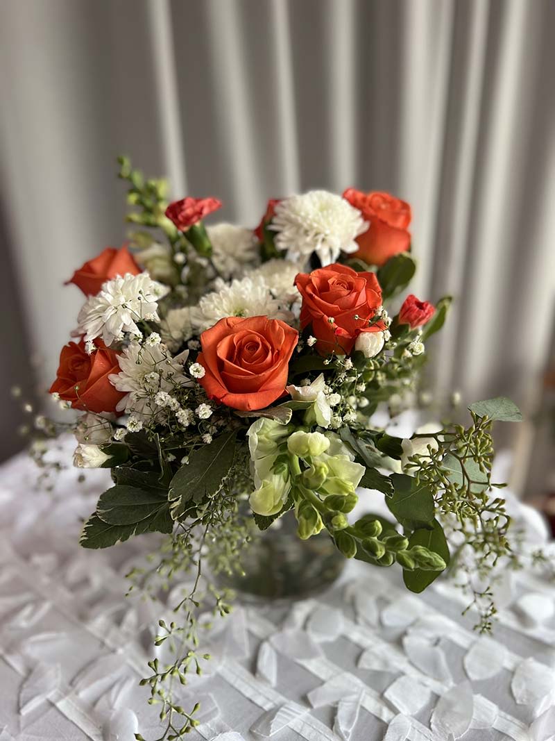 Orange roses and white daisies in a glass vase